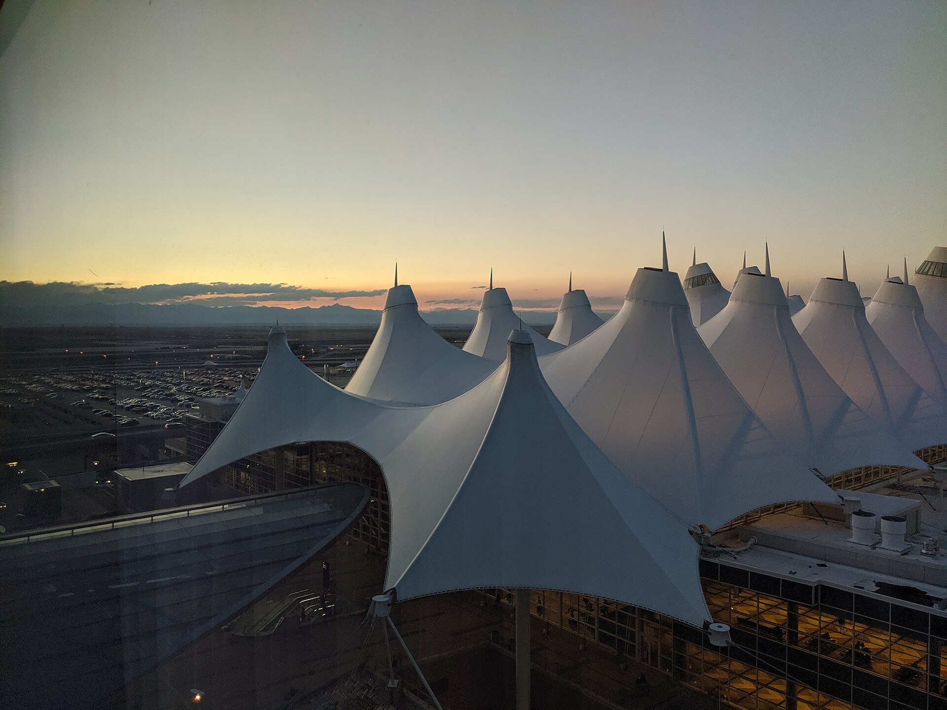 The real Jeppesen Terminal at Denver International Airport — its white tent peaks ranged against the Rockies at dusk