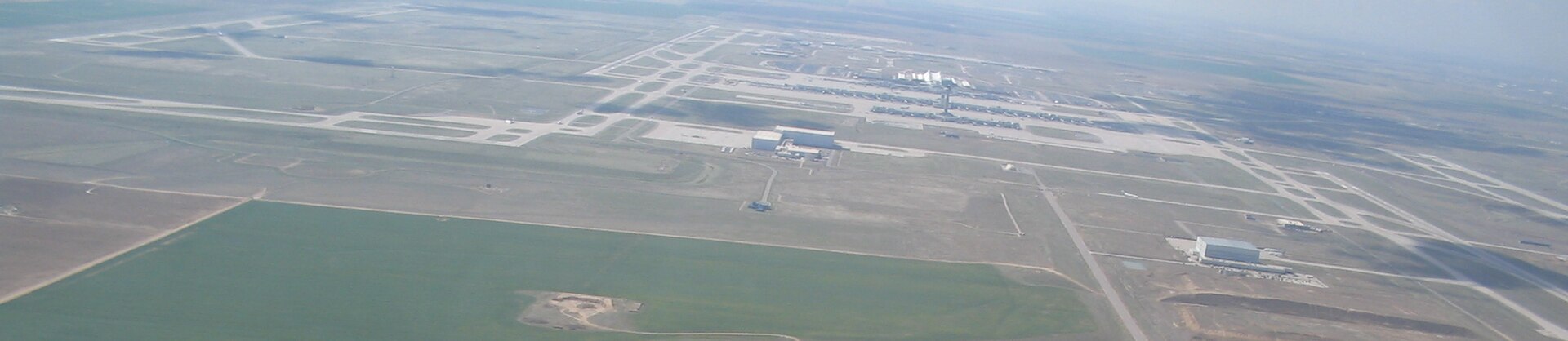 Denver International Airport seen from the air — runways scattered across empty plains, far out from the city