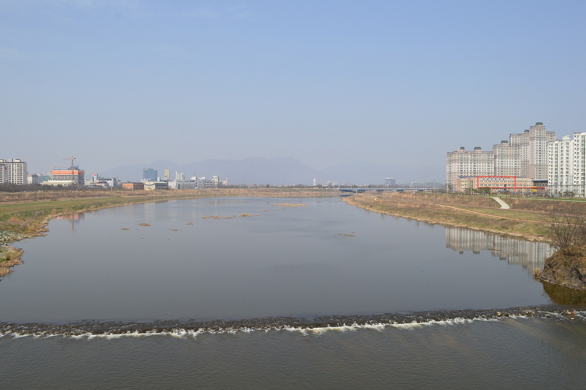The main channel of the Yeongsan River, into which the Deuldeul River flows, as it is today — broad still water, a low weir, and the grass flats along the bank (a stand-in view of the same river system, not the scene itself)
