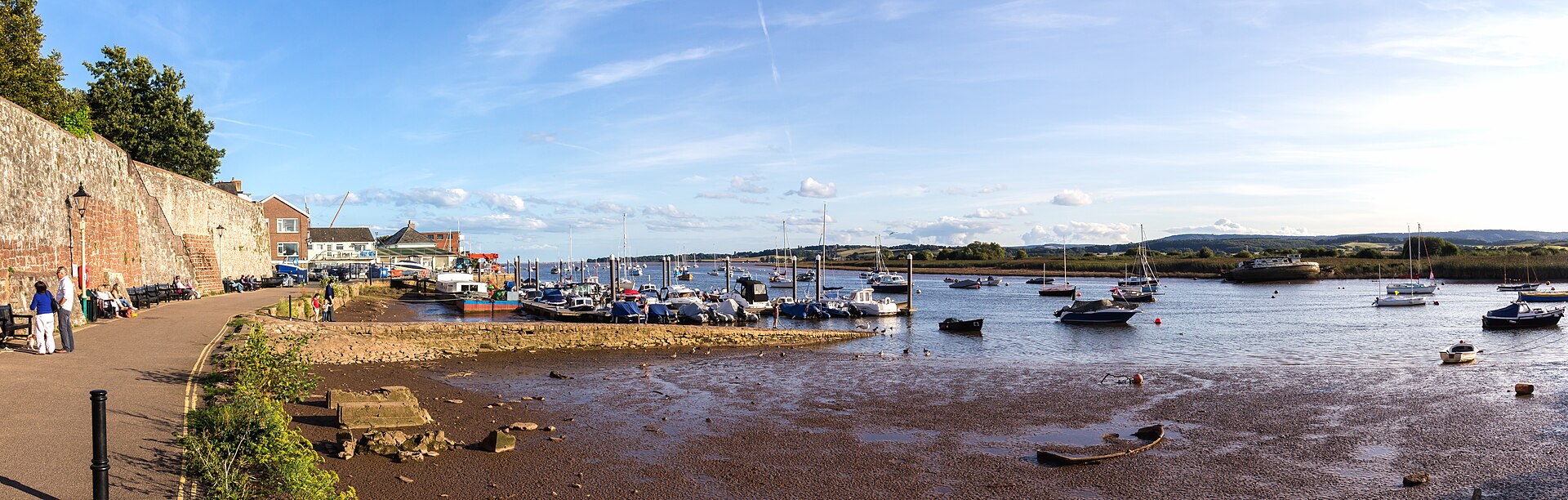 The Exe estuary at Topsham today: mudflats exposed at low tide, moored boats, and the old stone wall along the waterfront — one of the villages the footprints were said to have passed through in 1855.