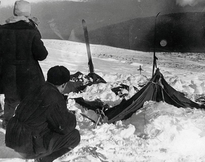 The tent as the search party found it on 26 February 1959: collapsed and buried in snow, with two searchers examining it. The image that has come to stand for the whole case.