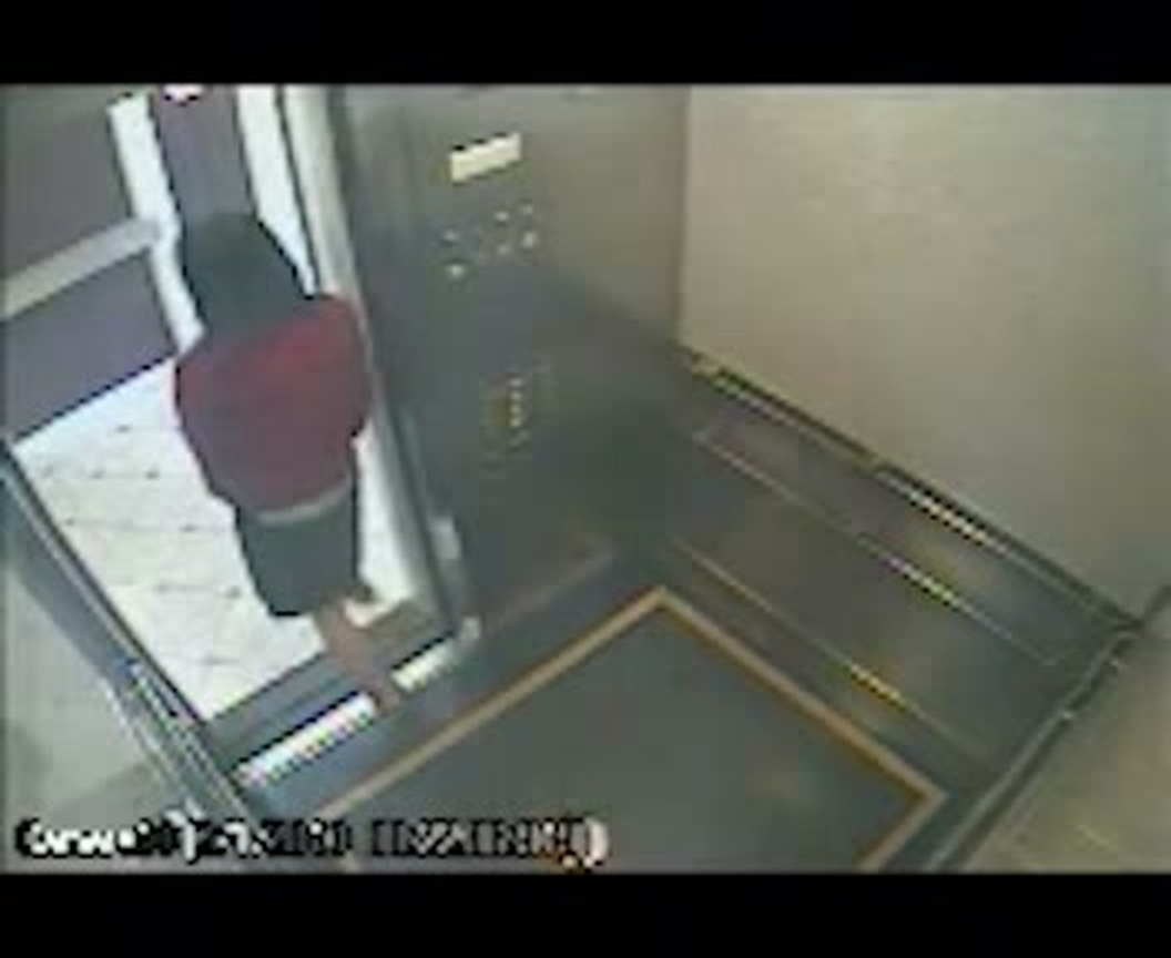 A frame from the elevator security footage released by the LAPD: a figure in a red hooded top standing in the open doorway. (The original recording is 352×288 pixels, hence the limited image quality.)