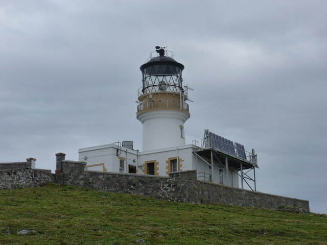 The Flannan Isles lighthouse as it stands today, the tower and the keepers' buildings behind a low stone wall
