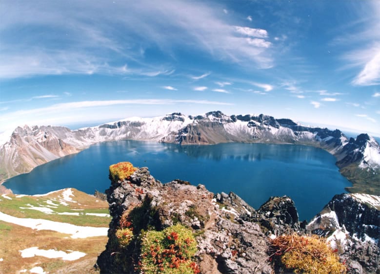 The still surface of Tianchi — "Heaven Lake" — under a clearing sky. (Bdpmax / CC BY-SA 3.0)