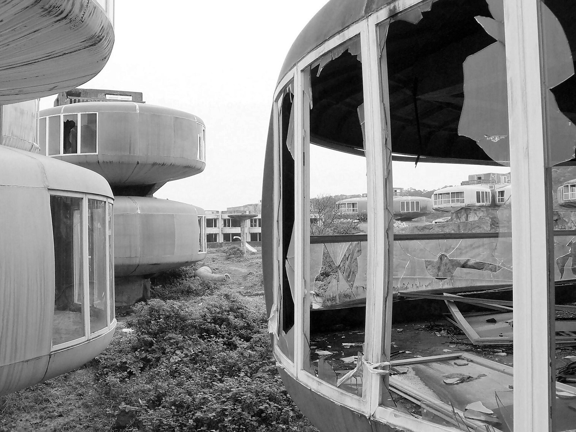 The complex seen from inside the ruins — pods sunk in weeds and debris (Wikimedia Commons)