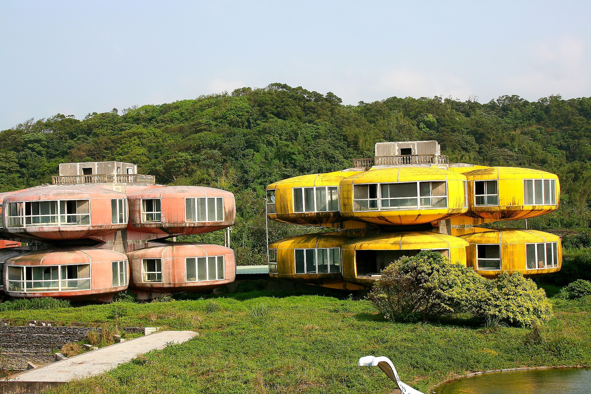 The Sanzhi pod houses before demolition — pink and yellow pods lined up against the hills behind (Wikimedia Commons)