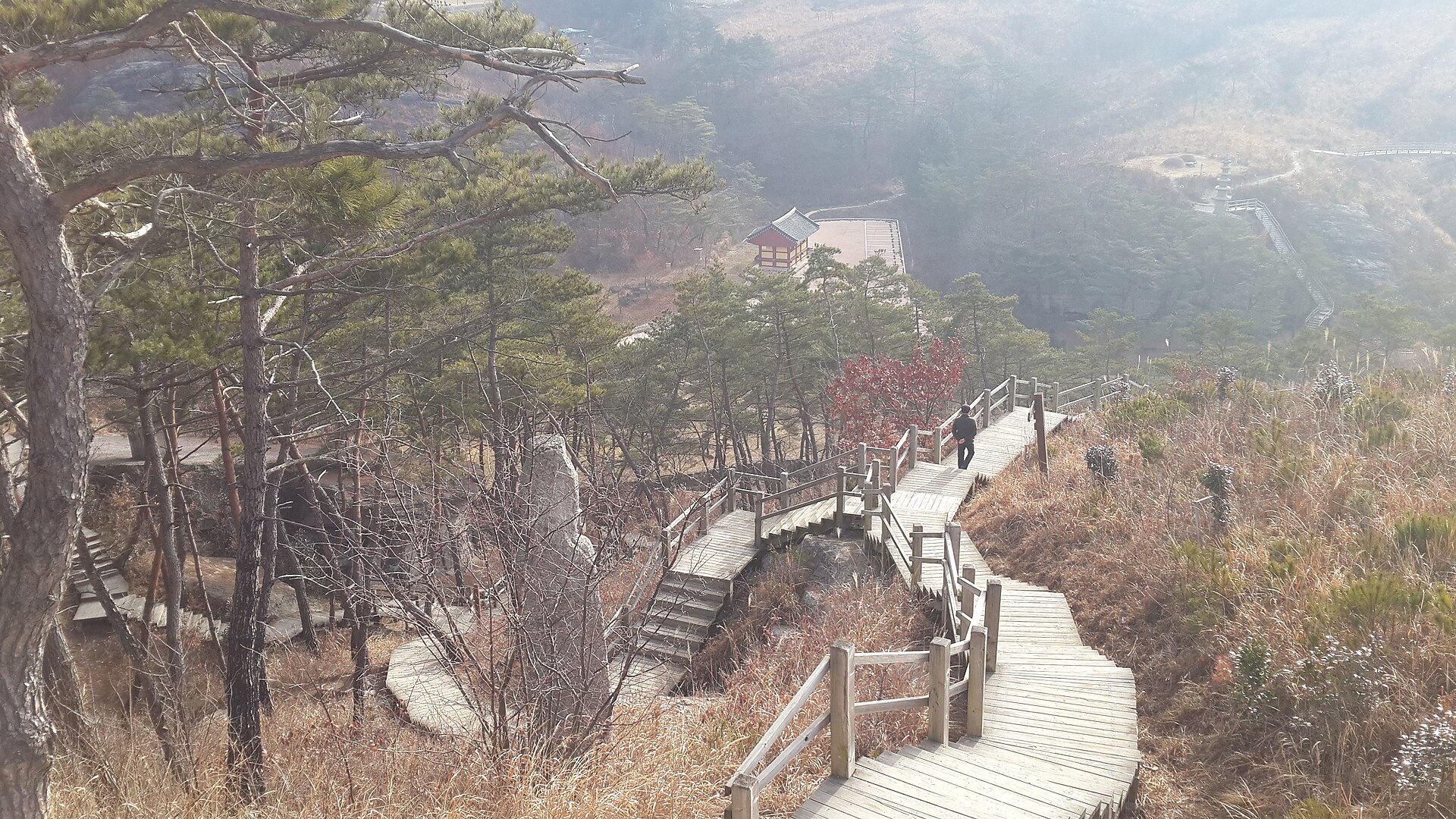 A boardwalk path descending through the Unjusa valley on a hazy winter day — the site as it stands today